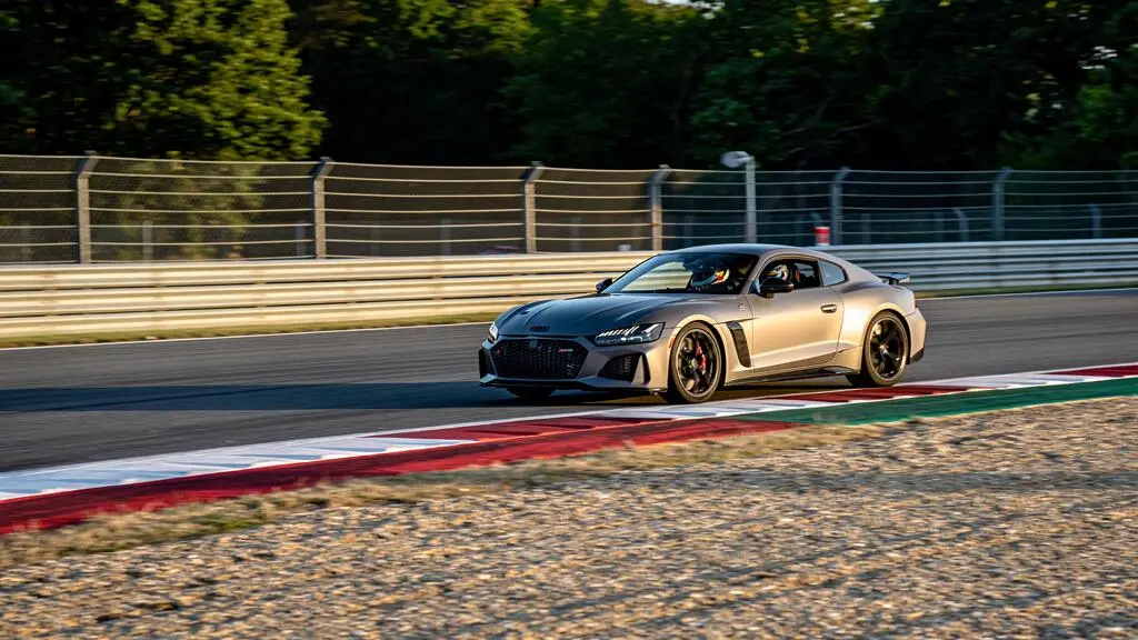 Une coupé sportif prend un virage sur un circuit homologué, avec vibreurs rouges et blancs en bord de piste.